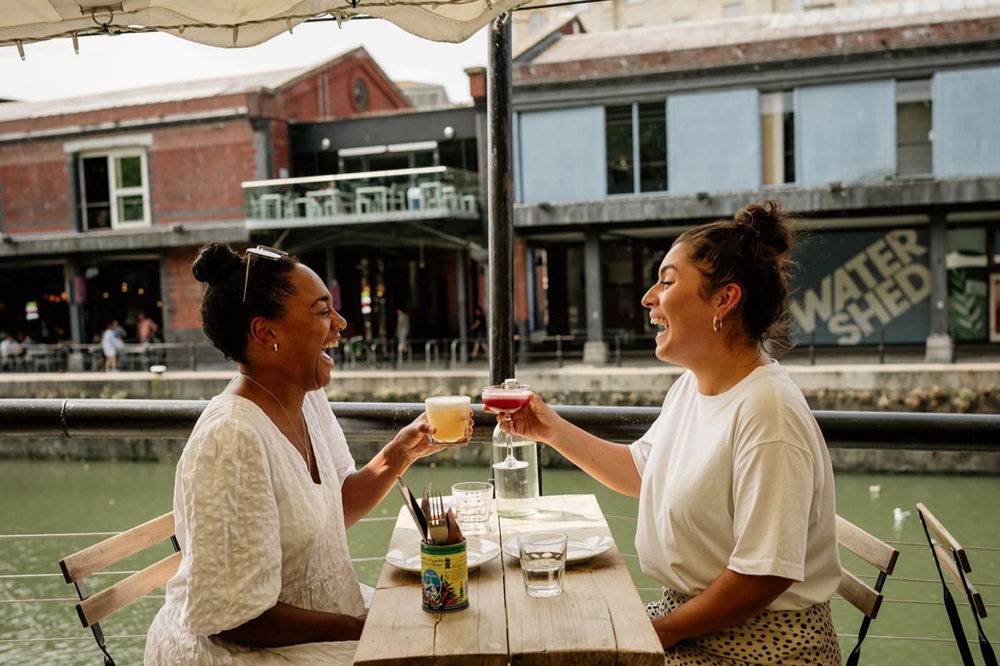 Two friends toasting cocktails on deck